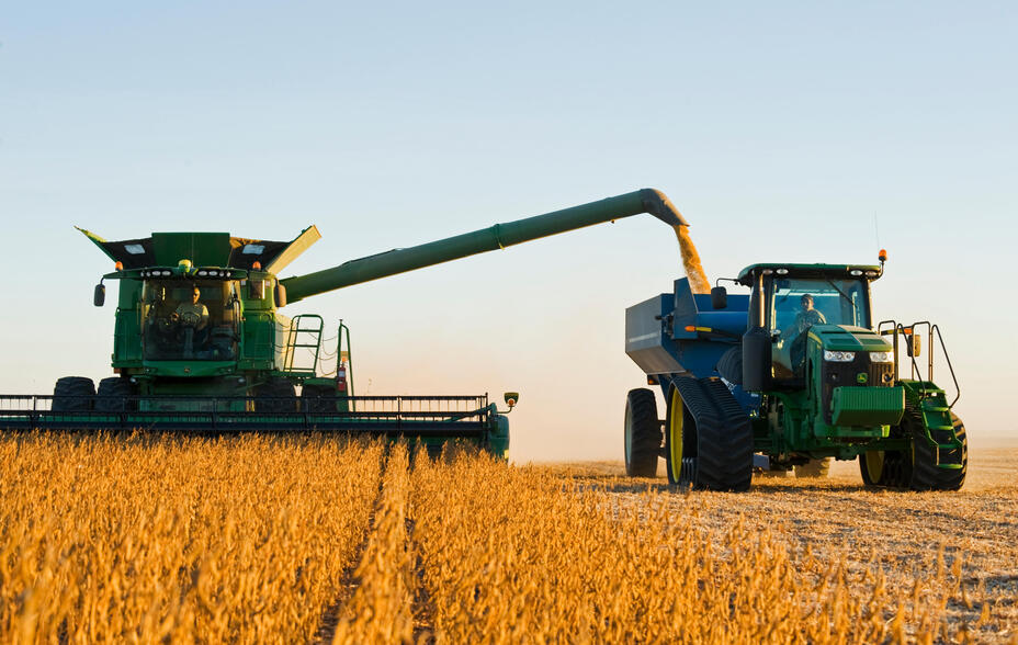 A combine harvester unloads soybeans into a grain wagon on the go during the harvest